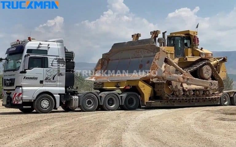 Semi-remorque lourde à châssis surbaissé transportant un gros bulldozer jaune, démontrant la capacité de charge élevée et la conception robuste de la remorque.
